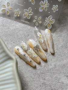 Macro view of 3D embossed frangipani nail stickers with glitter and gold foil accents