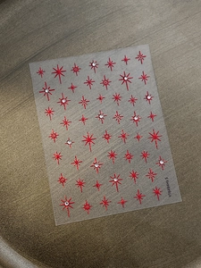 Detailed macro shot of red star nail stickers featuring sparkling clear rhinestones