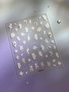 Macro view of 3D embossed floral and butterfly white nail art stickers with small pearls