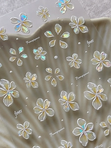 Close-up of 5D embossed frangipani nail art stickers with iridescent pearlescent finish