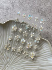 Macro detail of 3D holographic frangipani nail art stickers with embossed floral textures