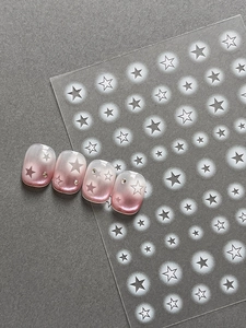 Detailed view of star nail art stickers applied on pink cat-eye gel polish with rhinestones