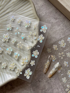 Detail showing 3D embossed white frangipani nail stickers with iridescent shell finish