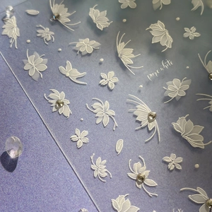 3D white embossed nail art stickers with butterfly and flower designs on purple background