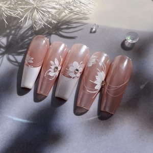Elegant nude pink coffin press-on nails with white floral patterns and crystal accents