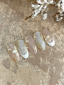 Détail de stickers à ongles tulipes dorées avec perles sur faux ongles rose nude