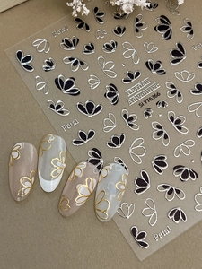 Détail macro de stickers à ongles floraux avec reliefs de pétales argentés et noirs