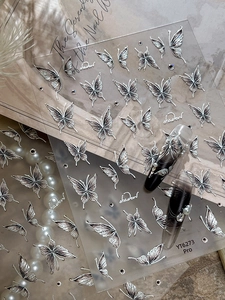 Detail view of 3D metallic silver butterfly nail stickers with embossed texture and patterns
