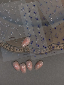 Detail of holographic star nail art stickers on pink nails with aesthetic gold tray