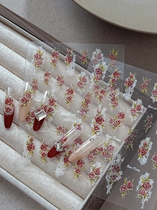 Detailed view of red rose nail stickers with floral patterns on a manicured nail tip