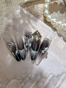 Detailed macro of handmade press-on nails with silver butterfly charms and white pearls