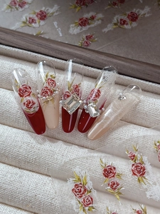 Macro detail of red rose stiletto press-on nails with 3D crystal and pearl accents