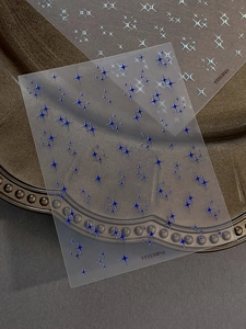 Detail view of holographic silver and blue four-pointed star nail art decals