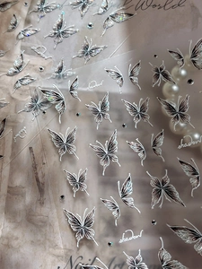 Macro shot of 3D embossed silver butterfly nail stickers with pearlescent necklace accents