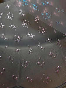 Macro detail of holographic cross star nail stickers with purple and blue iridescent sheen