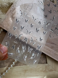 Macro detail of 3D embossed silver butterfly nail stickers with iridescent finish YT6273