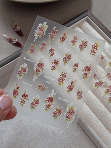 Detailed macro view of 5D embossed red rose nail stickers with delicate white lace patterns