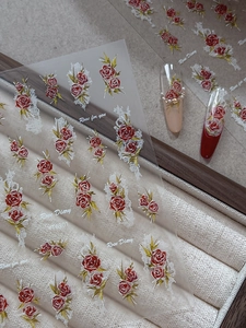 Macro detail of 3D embossed red rose nail stickers with delicate white lace textures