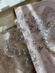 Detail of laser silver butterfly nail stickers with 3D embossed texture on elegant background