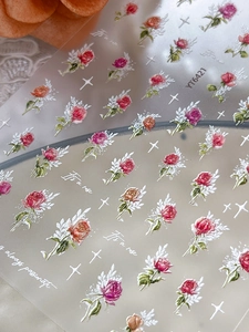 Macro detail of 3D embossed rose nail stickers with floral patterns and gold lettering