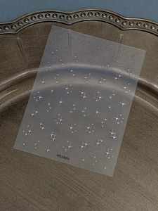 Detailed view of iridescent purple star nail stickers on a metallic embossed plate