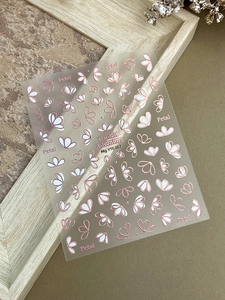 Détail de stickers nail art floraux avec pétales blancs et bords dorés rose sur papier
