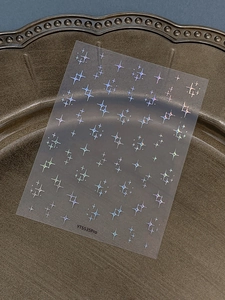 Macro shot of silver laser holographic four-pointed star nail art stickers on a metal tray