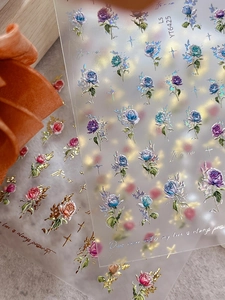 Close-up of 5D embossed rose nail stickers with laser iridescent finish and gold edges