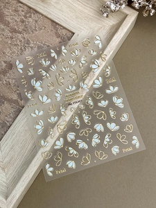 Détail d'autocollants pour ongles fleurs bronzantes avec contours dorés et pétales bleus