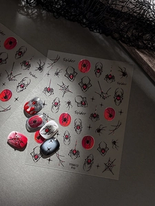 Macro detail of Gothic spider and cobweb nail art stickers on black and red manicure