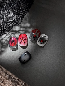 Detail of Halloween press-on nails featuring 3D spider webs and red gem accents