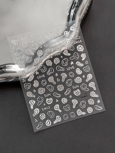 Macro detail of silver 3D embossed nail stickers featuring smile faces and stars
