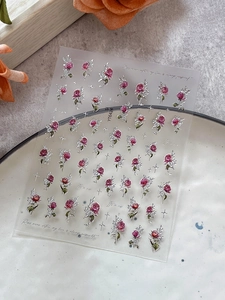 Detail of embossed red rose nail stickers with metallic silver outlines and star accents