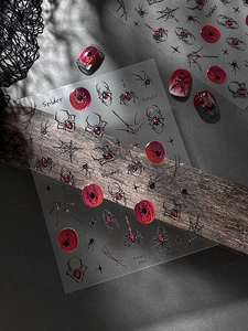 Detail of spider web nail stickers with red gem accents for Halloween nail art