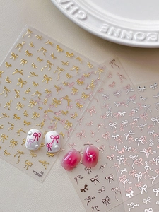 Close-up of bow nail stickers in gold and silver showing realistic application on nails