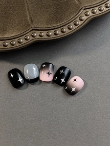 Detail of star pattern nail art with black and pink gradient finish and metal beads