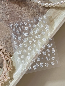 Gros plan d'autocollants nail art fleurs en plâtre gaufré blanc pour un style féminin doux