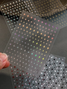 Close-up of minimalist laser star nail art stickers in various colors and metallic finishes