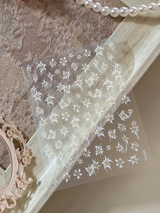 Détail d'autocollants nail art fleurs en relief avec pétales blancs et pistils dorés