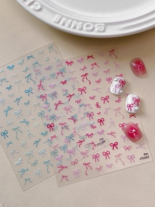 Detailed view of colorful bow nail stickers applied with pearl accents on a soft background