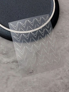 Macro detail of silver V-shape geometric line nail stickers with metallic reflective finish