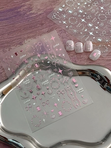 Close-up of rose gold bow and heart 3D embossed nail stickers on a metallic tray
