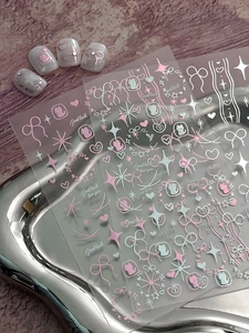 Detail of rose gold bow and heart nail stickers with cat motifs on a metal display tray