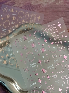 Macro view of rose gold bow nail stickers featuring heart, star and cat silhouette patterns
