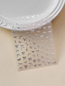 Detailed view of silver bow nail stickers YT5509 on a cream leather background