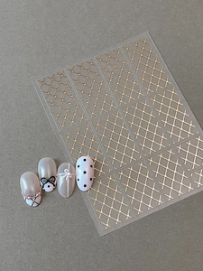 Détail d'autocollants à ongles dorés à carreaux avec micro-perles pour nail art élégant