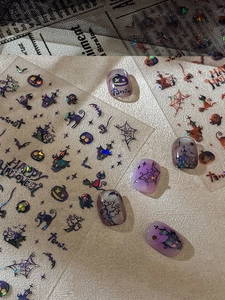 Macro shot of Halloween pumpkin nail stickers with laser effect and spider web patterns