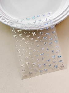 Macro shot of 3D aurora laser ribbon bow nail stickers on white leather and porcelain