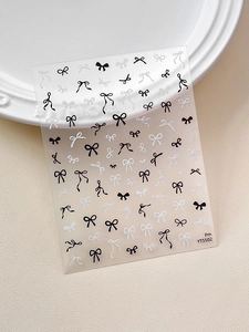 Detail of YT5502 black and white bow nail stickers on a white ceramic plate