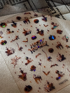 Macro detail of laser iridescent Halloween nail stickers with pumpkins and spider webs